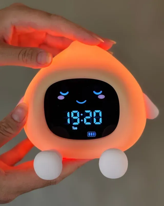 Lumulu sömntränare i orange silikon med sovande ansikte och digital tidsvisning på displayen
